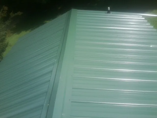New green metal panels meeting at the ridge of a roof — Flat Roof Repair work by our crew in Arden