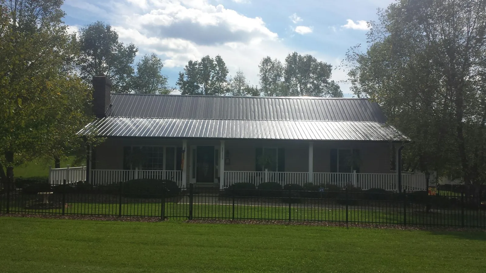 Gray metal roof on a brick ranch with a full width front porch — Gutter Guard Installation work by our crew in Arden