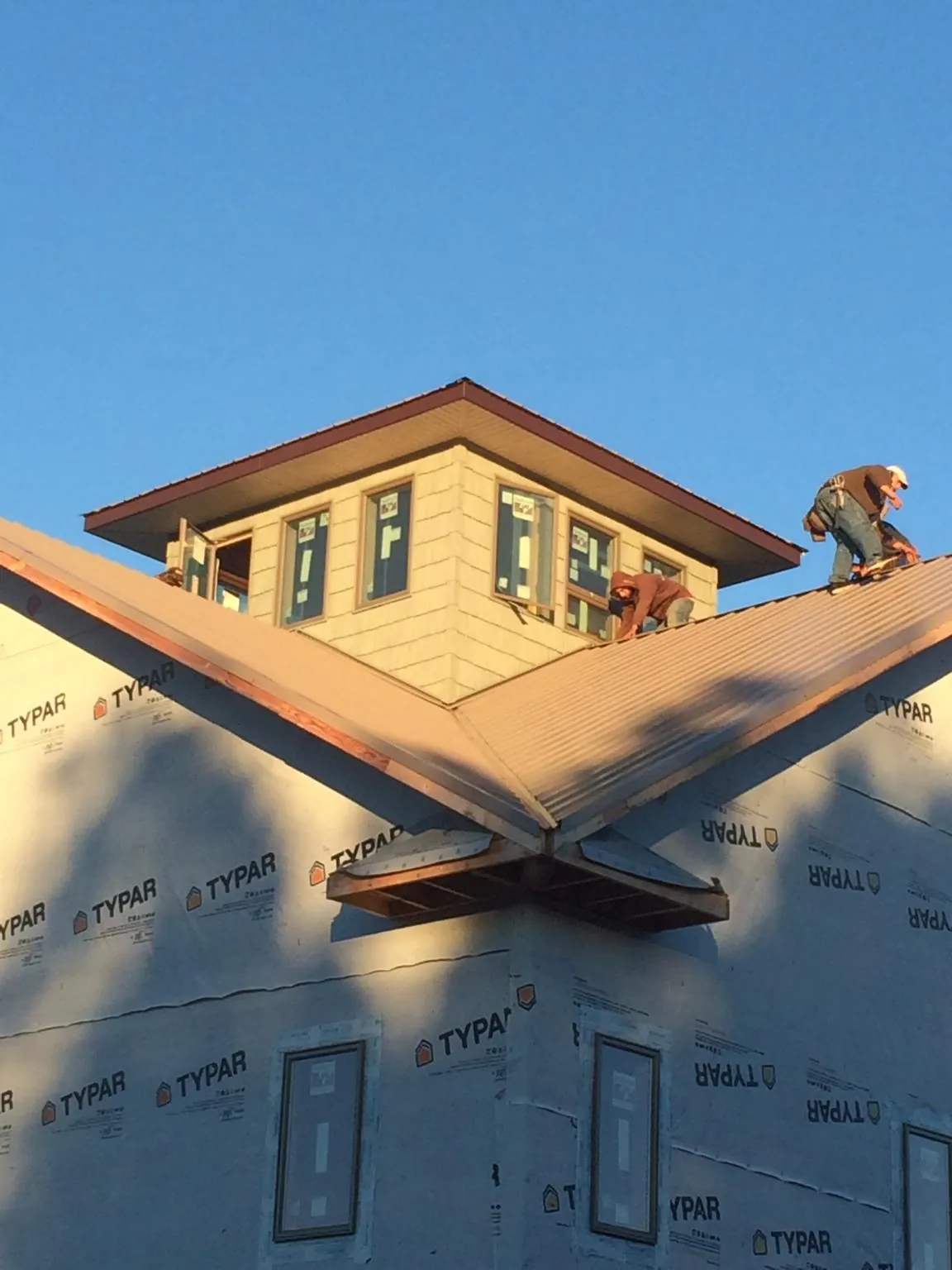 Roofers working around a rooftop cupola on a new metal roof at sunset — Roof Waterproofing in Arden by Roofing Brothers